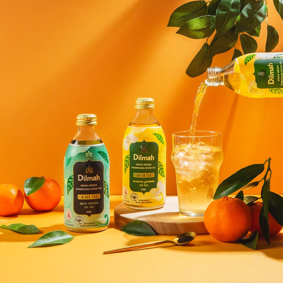 Dilmah black and green iced tea bottles with a glass of iced tea.