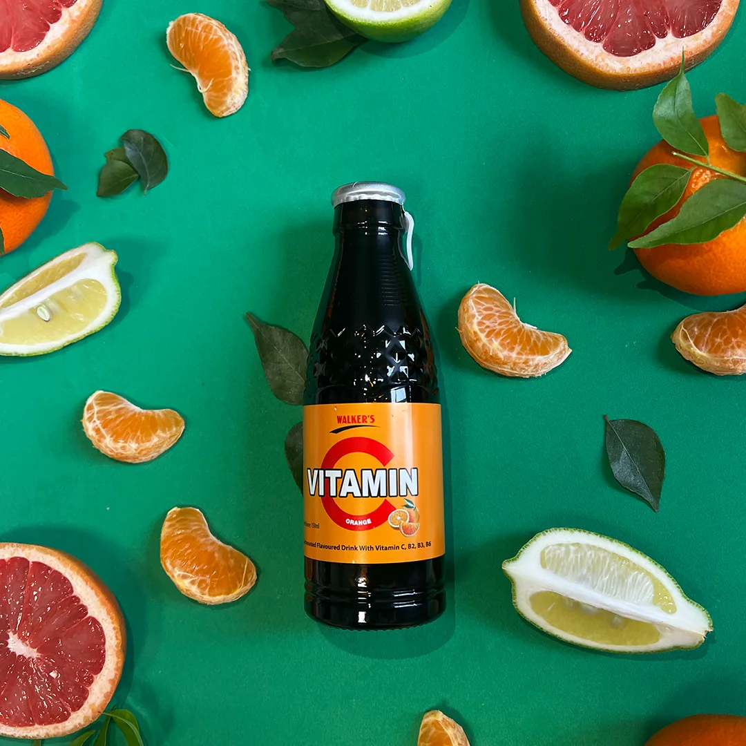 Walker's Vitamin C orange drink bottle surrounded by citrus fruit.